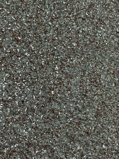 Close-up of gray and brown quartz-style flake epoxy floor with glossy topcoat installed by IronCoat Epoxy Co. in DFW