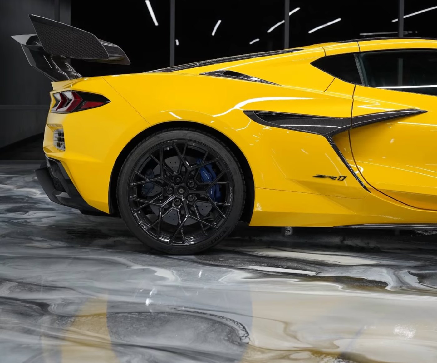 Yellow Corvette ZR1 parked on a white and gray marble-look metallic epoxy showroom floor installed by IronCoat Epoxy Co. in DFW